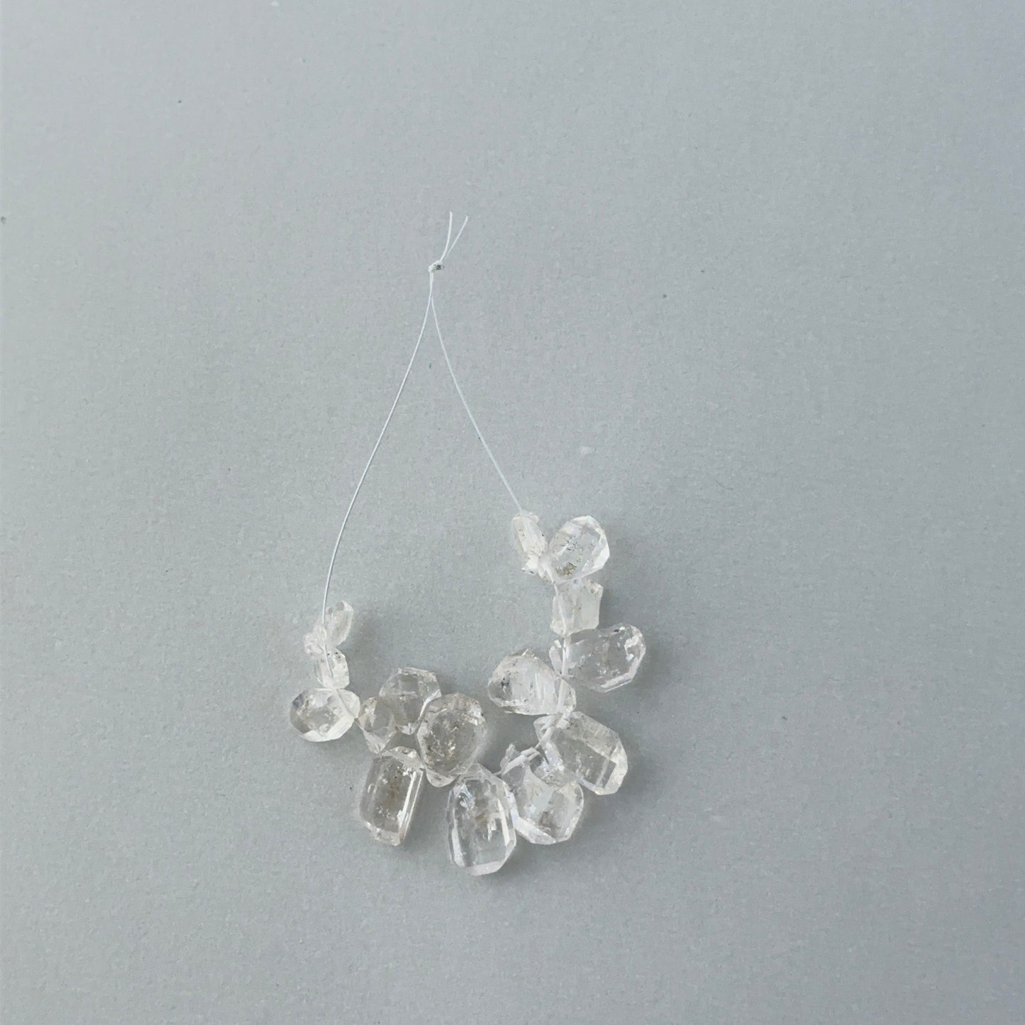 Close up of 14 piece Herkimer Diamond strand showing raw crystal geometry and 0.5mm drill holes