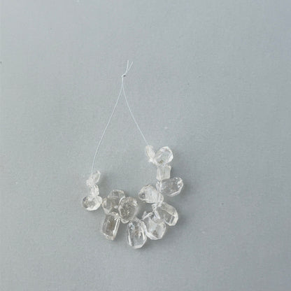 Close up of 14 piece Herkimer Diamond strand showing raw crystal geometry and 0.5mm drill holes