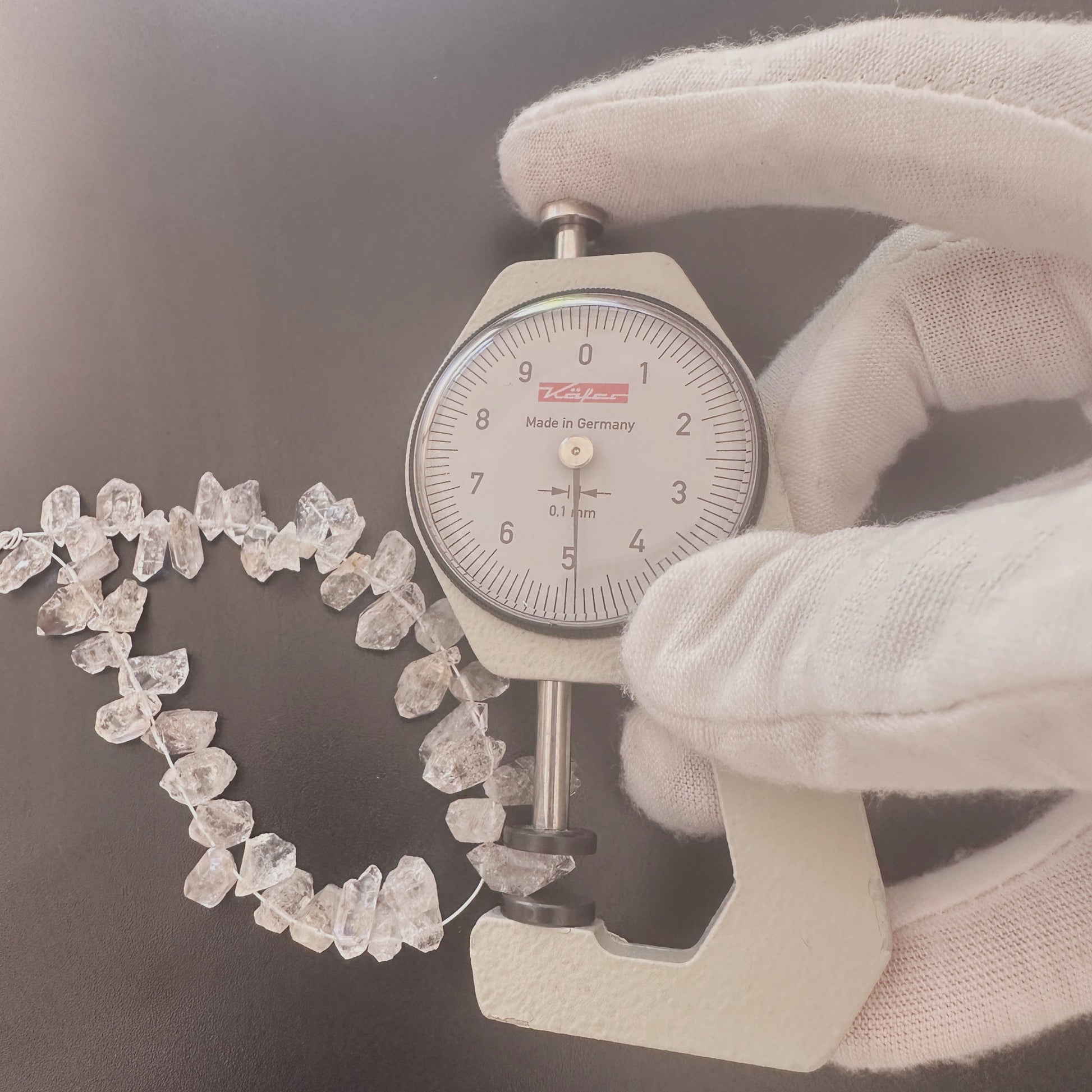 A dial gauge measures the Herkimer rough cut 4–5mm gemstone.