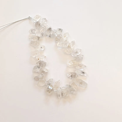 Herkimer diamond beads arranged in a line, highlighting their unique rough texture.