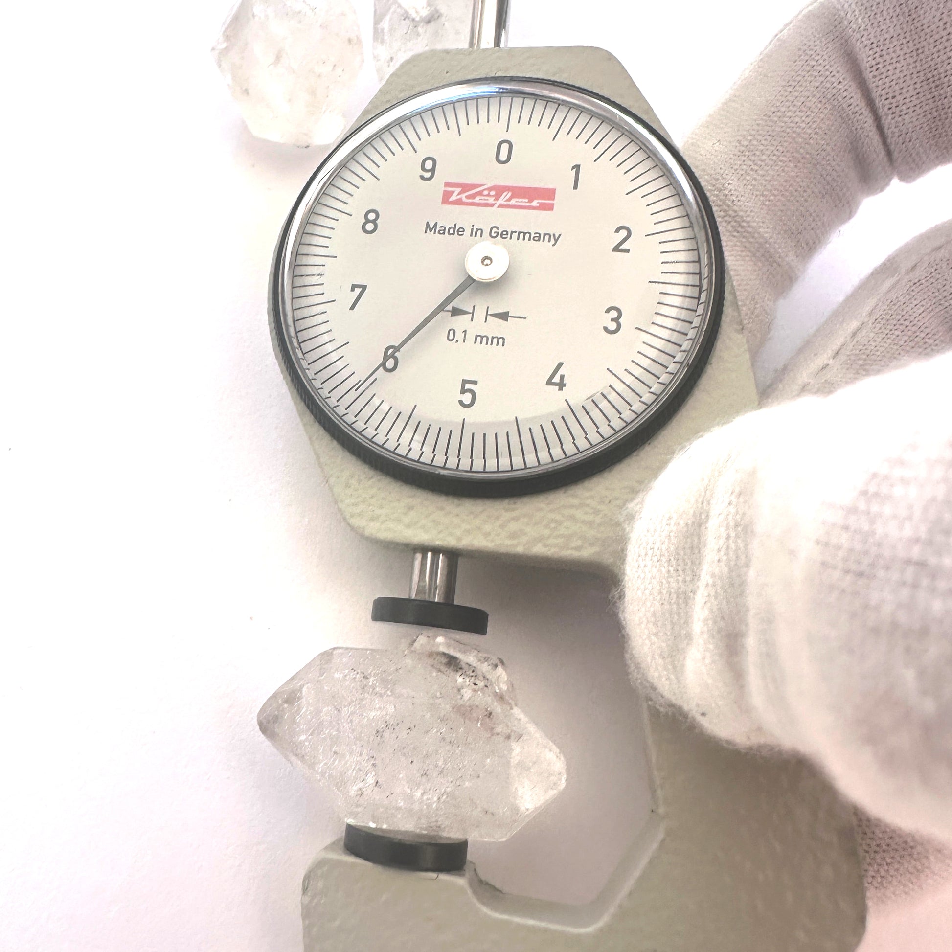 A dial gauge measures the Herkimer Diamond rough cut 15-17mm gemstone.