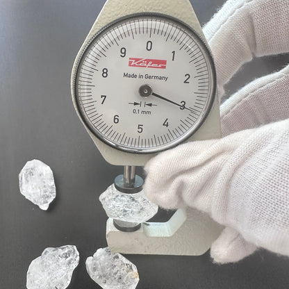 A dial gauge measures the Herkimer nugget rough cut 13–14mm gemstone.
