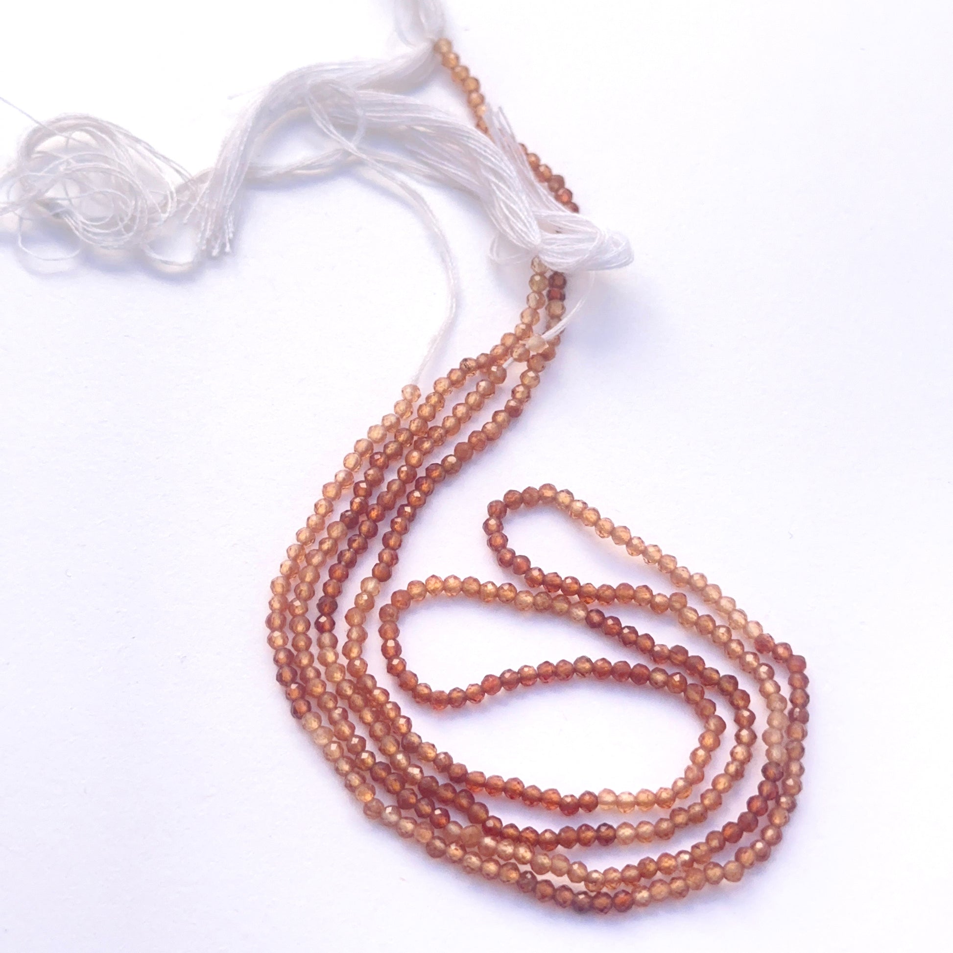  Close-up of natural gemstone beads showing faceting and rich hessonite colour. 