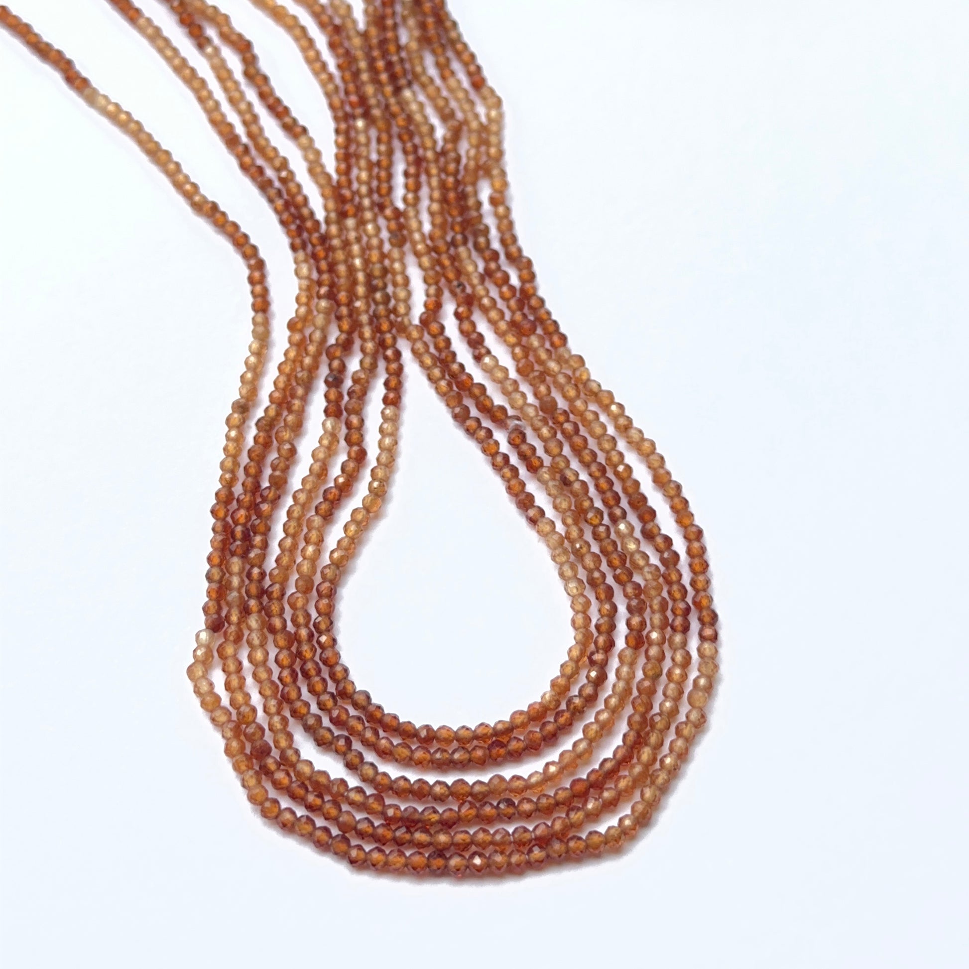Close‑up of hessonite faceted rondelles highlighting their polished cut and natural gemstone shine.