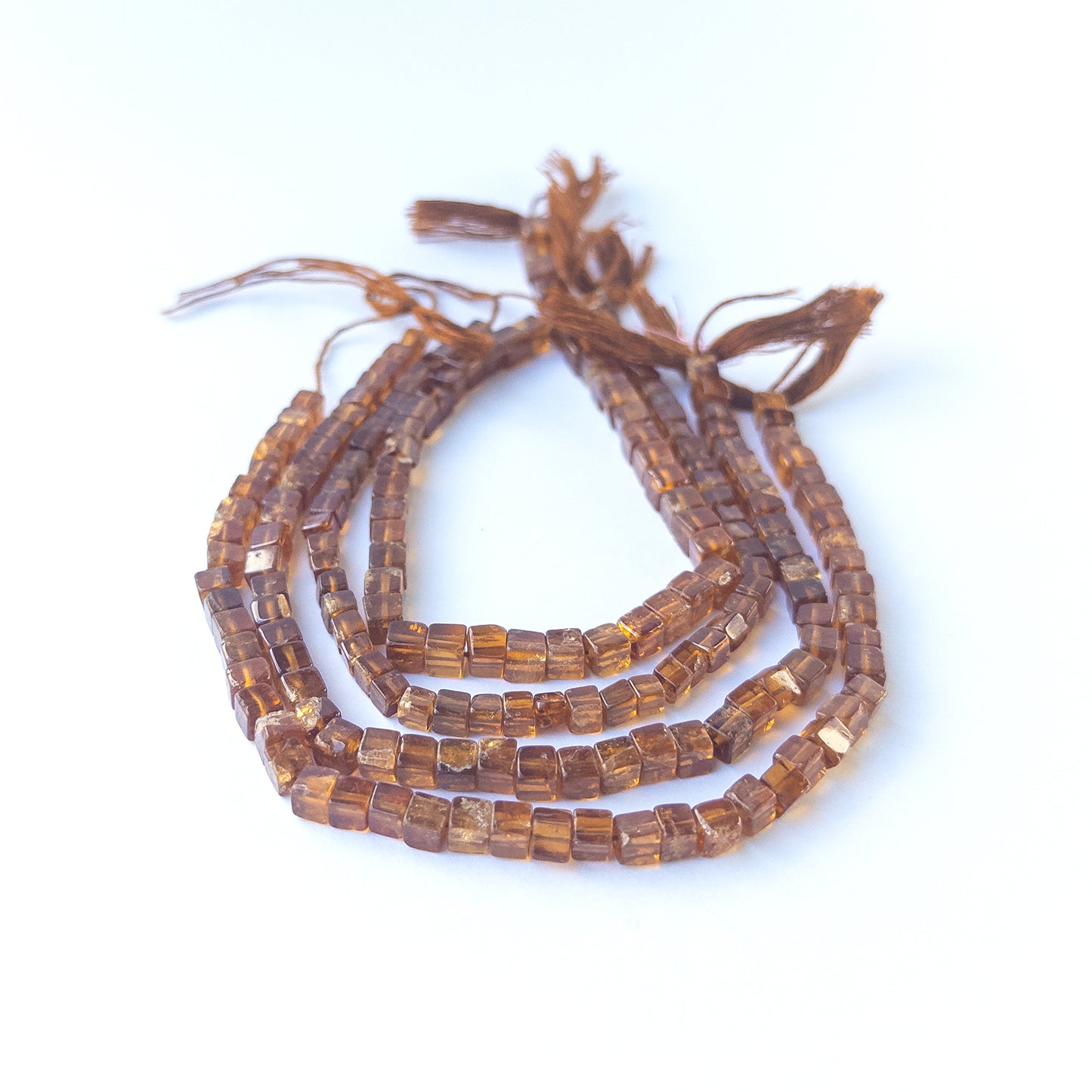 Hessonite smooth cube gemstone beads in warm honey‑brown tones arranged on a 20cm strand for handmade jewellery components.