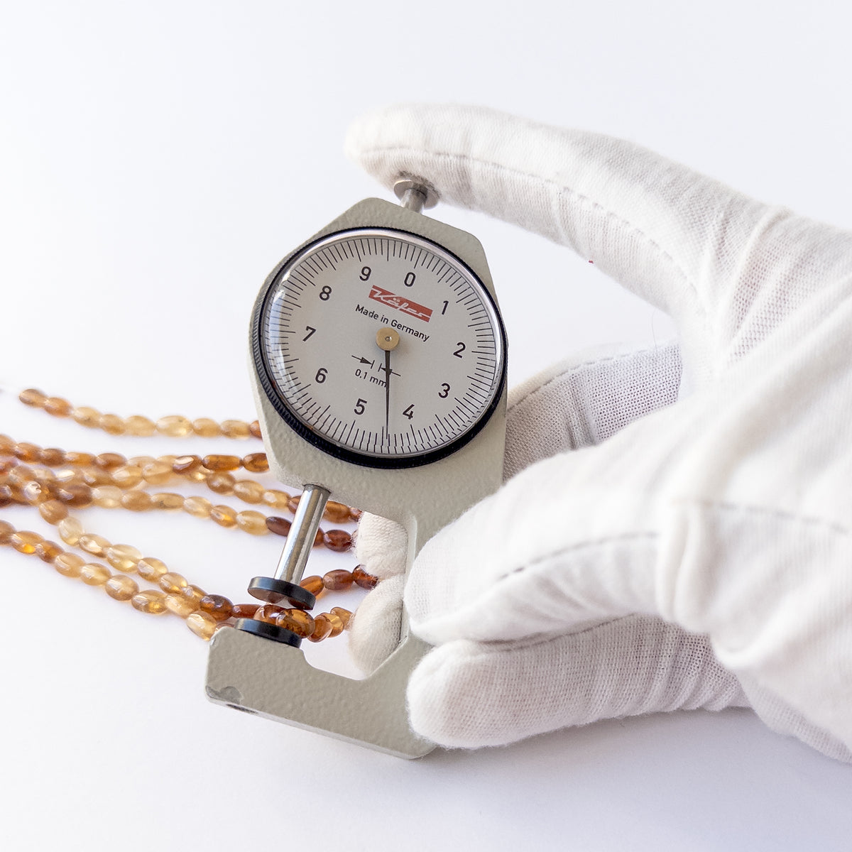 A dial gauge measures the Hessonite smooth oval 4–4.5mm gemstone.