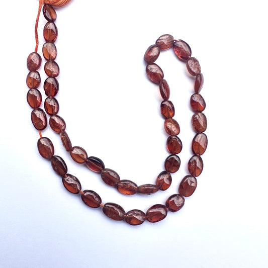 Smooth oval Hessonite beads in 7.5–9x6mm size strung on a 33cm strand.