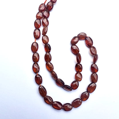 Close-up of natural gemstone beads featuring Hessonite in warm amber tones and polished finish. 