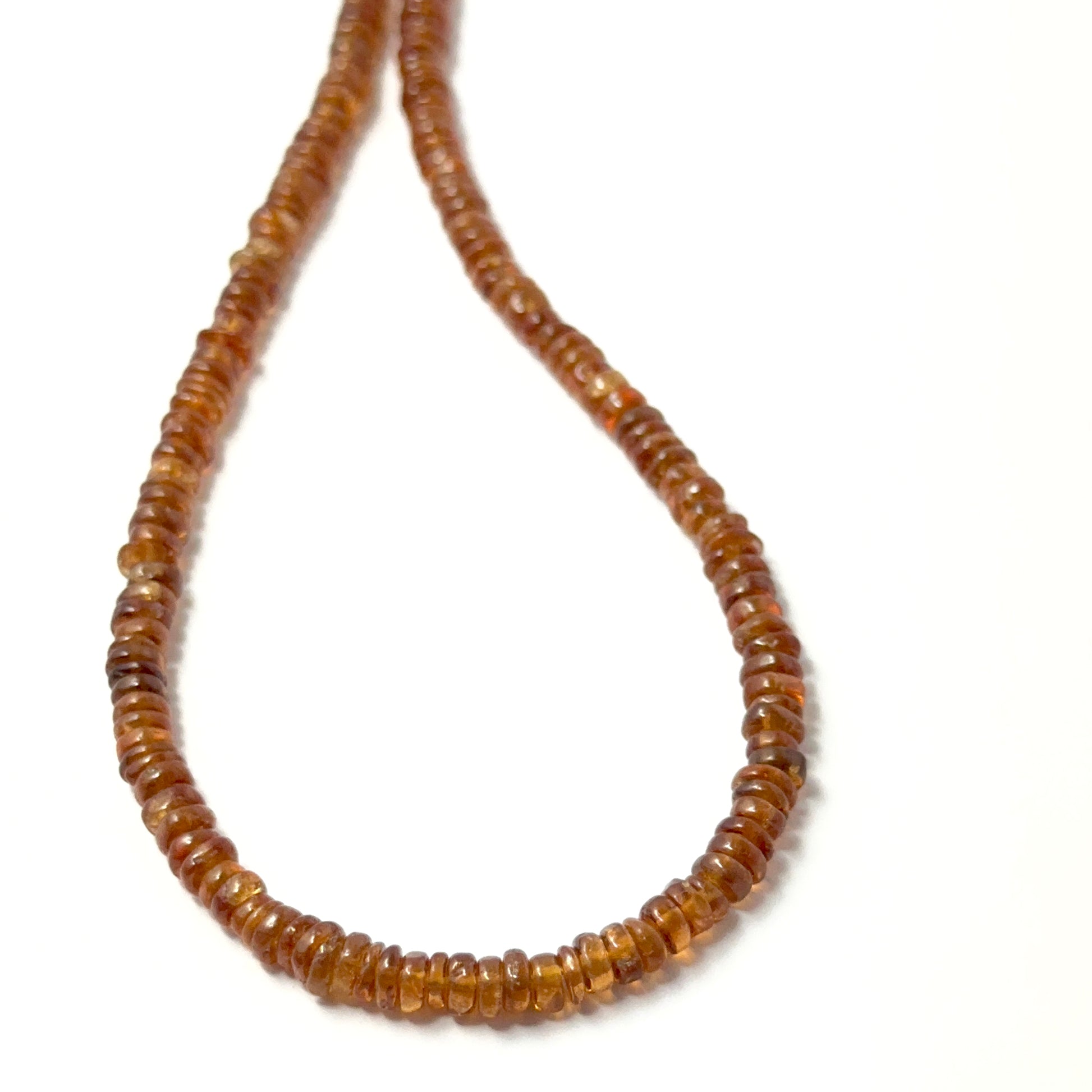 Close view of polished Hessonite smooth wheels arranged on a 26cm strand for handmade jewellery components.
