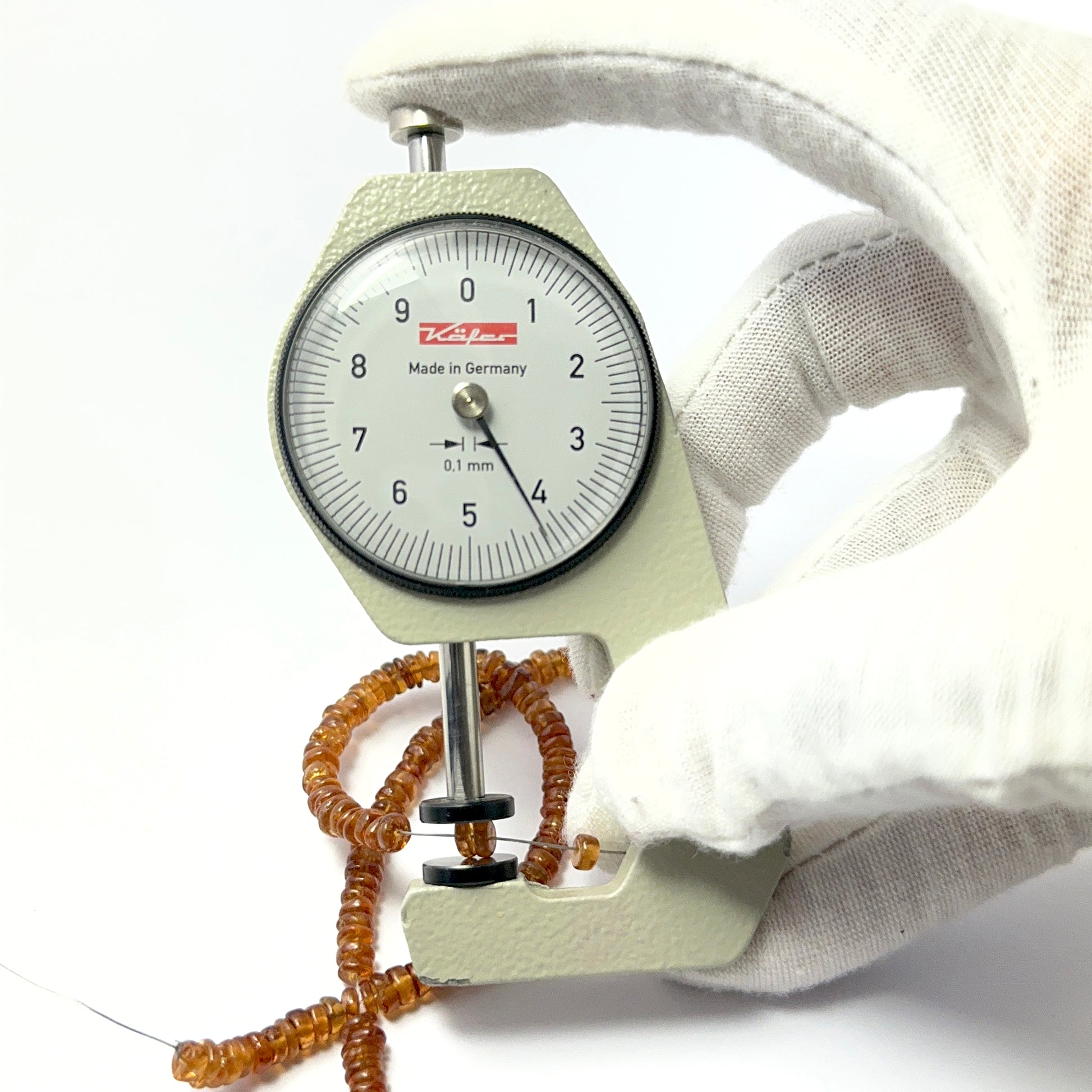 A dial gauge measures the Hessonite smooth wheel 4.3–4.6mm gemstone.