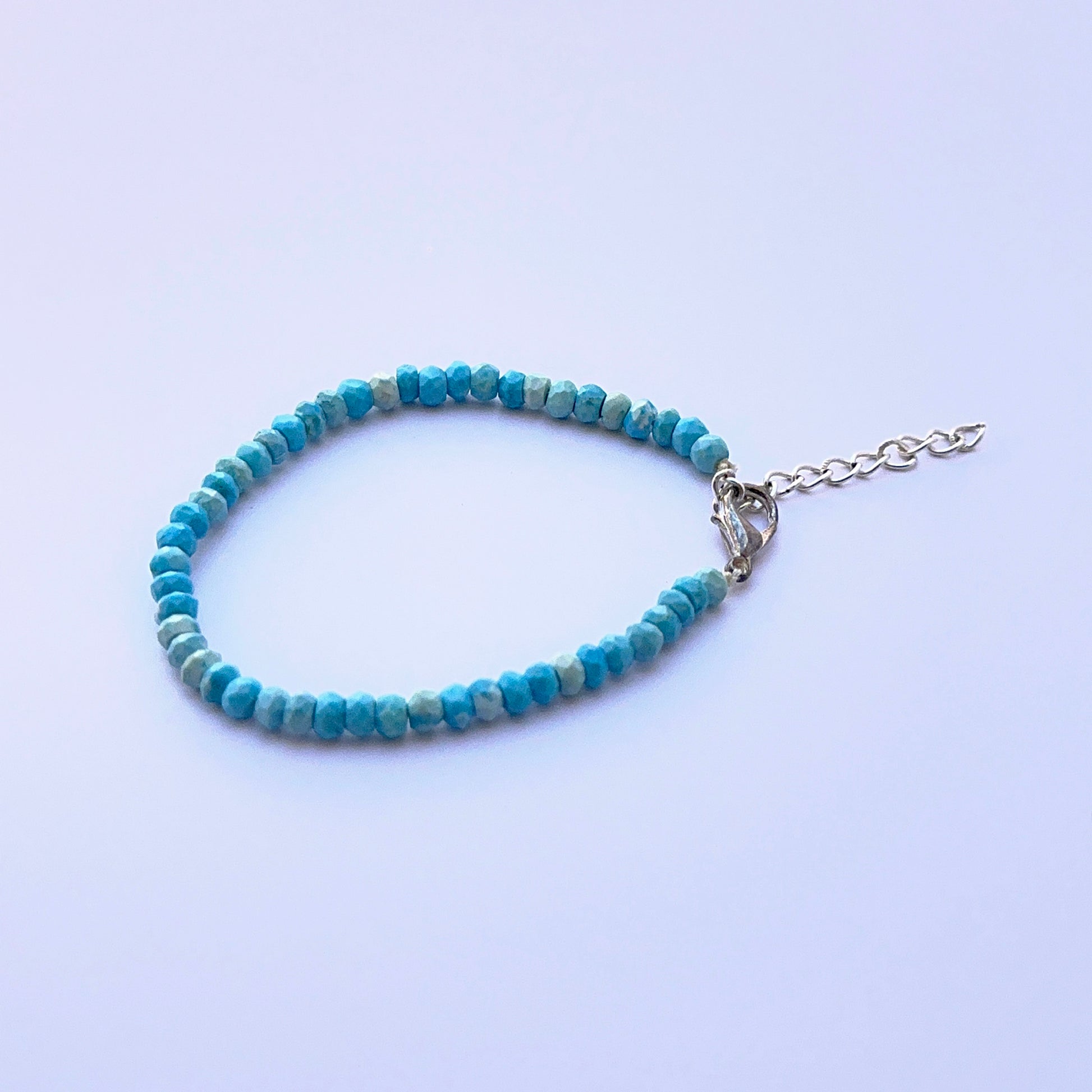 Close‑up of faceted howlite turquoise beads arranged on a polished bracelet.