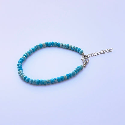 Close‑up of faceted howlite turquoise beads arranged on a polished bracelet.