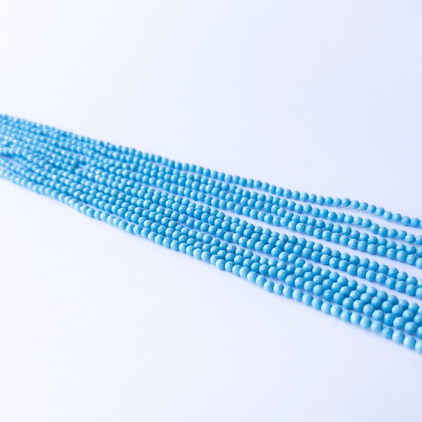 Genuine Howlite Turquoise gemstone beads in faceted rondelle cut, displaying polish, texture, and bold turquoise hues.