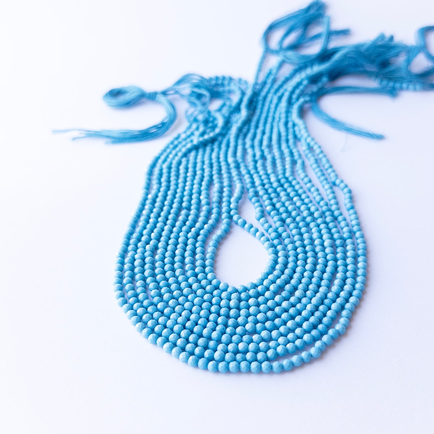 Strands of Howlite Turquoise faceted rondelle gemstone beads arranged neatly, showcasing their fine cut and vibrant colour.