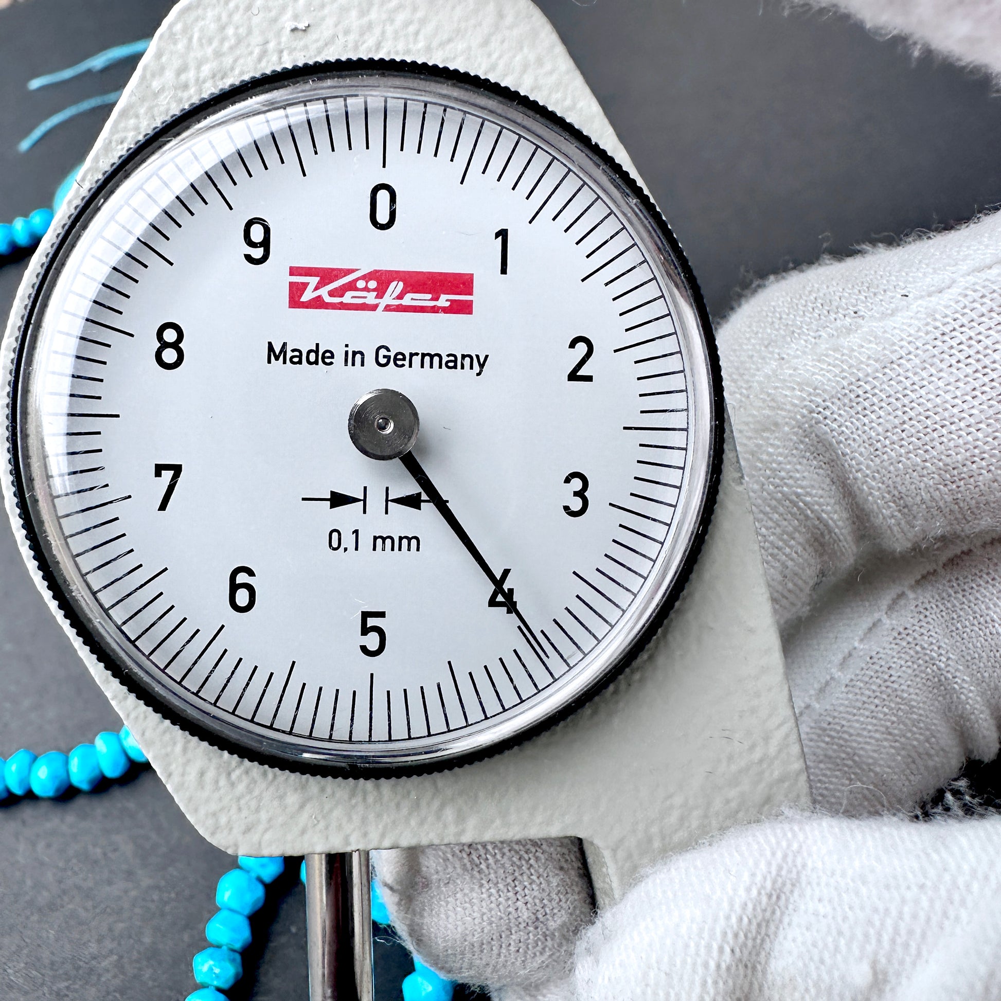 A dial gauge measures the Howlite Turquoise faceted rondelle 4mm gemstone