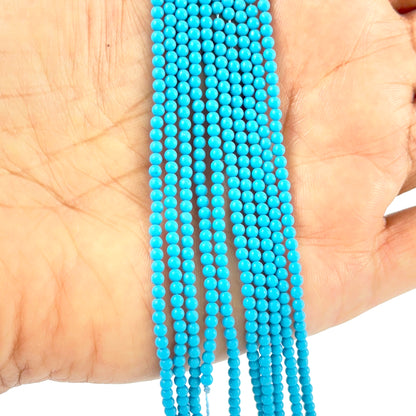 A person holds delicate strands of Howlite Turquoise beads, showcasing their smooth design.