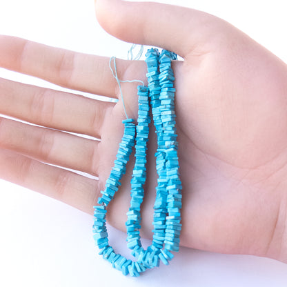 A person holds delicate strands of Howlite Turquoise beads, showcasing their smooth square heishi design.
