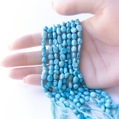 Genuine Howlite Turquoise beads displaying bright blue tones, polished surfaces, and a neatly arranged 32cm strand for jewellery design.