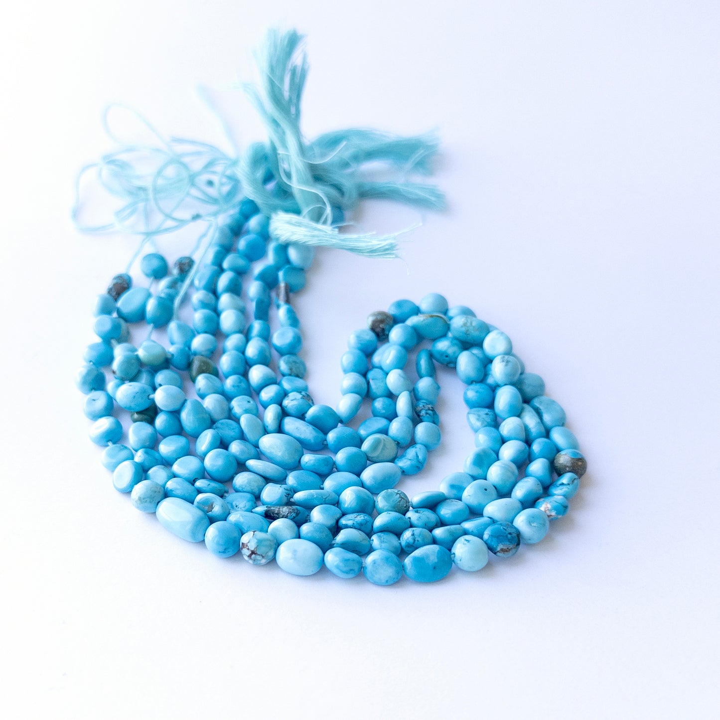 Handmade jewellery components featuring natural Howlite Turquoise smooth tumbles, highlighting their colour and glossy finish.