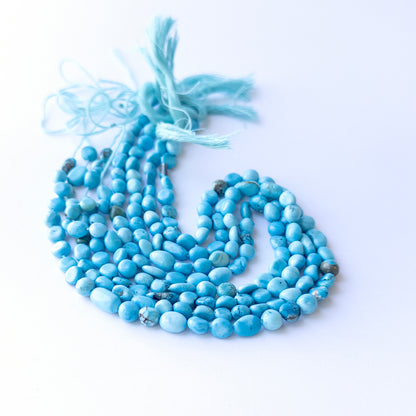 Handmade jewellery components featuring natural Howlite Turquoise smooth tumbles, highlighting their colour and glossy finish.
