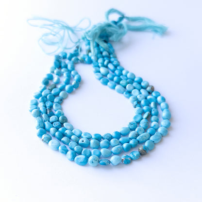 Close‑up of authentic Howlite Turquoise smooth tumble beads showing their shine and consistent 6–6.5mm sizing.