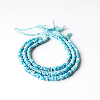 Howlite Turquoise smooth wheel heishi beads arranged in a strand showing bright blue colour and polished finish.