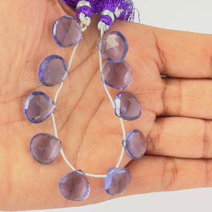 A person holds delicate strands of Hydro beads, showcasing their faceted briolette design.