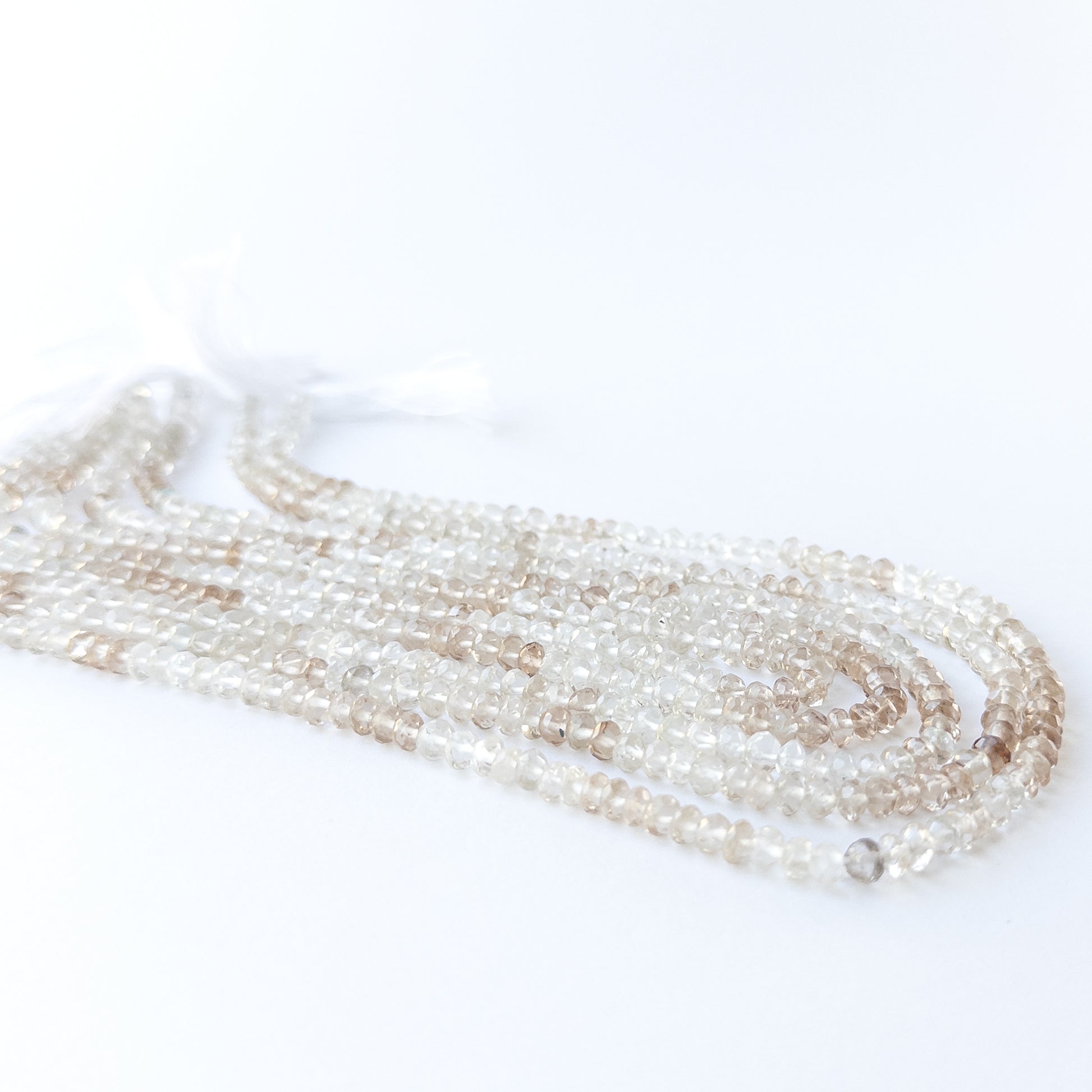 Handmade jewellery components featuring faceted Imperial White Topaz rondelle beads in a neatly arranged strand.