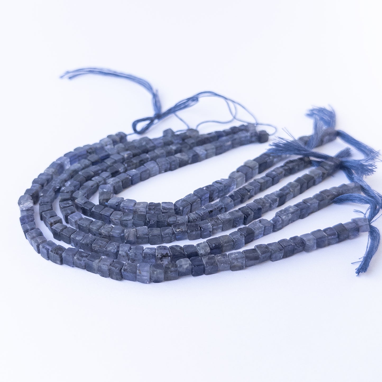 Handmade jewellery components featuring natural iolite smooth cube beads in a neatly aligned strand.