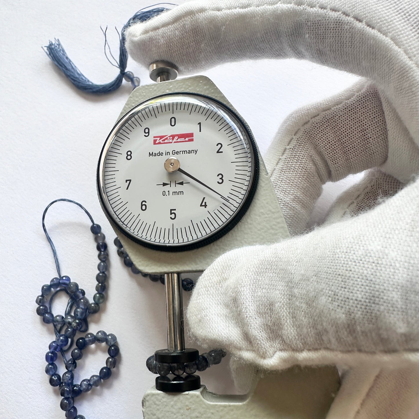 A dial gauge measures the Iolite smooth round 3.5mm gemstone.