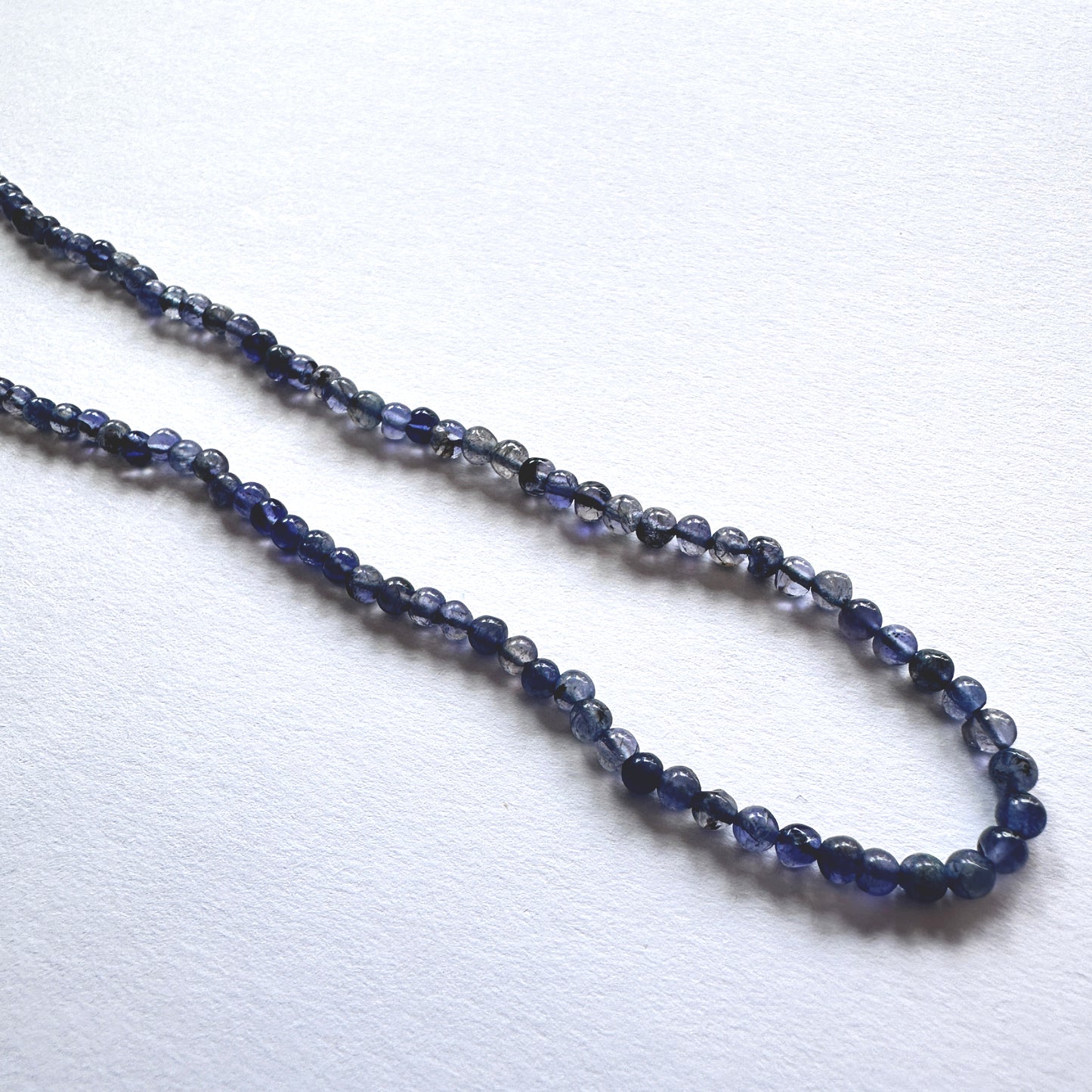 Stone beads with smooth Iolite arranged neatly, showcasing clarity and colour depth for handmade jewellery components.