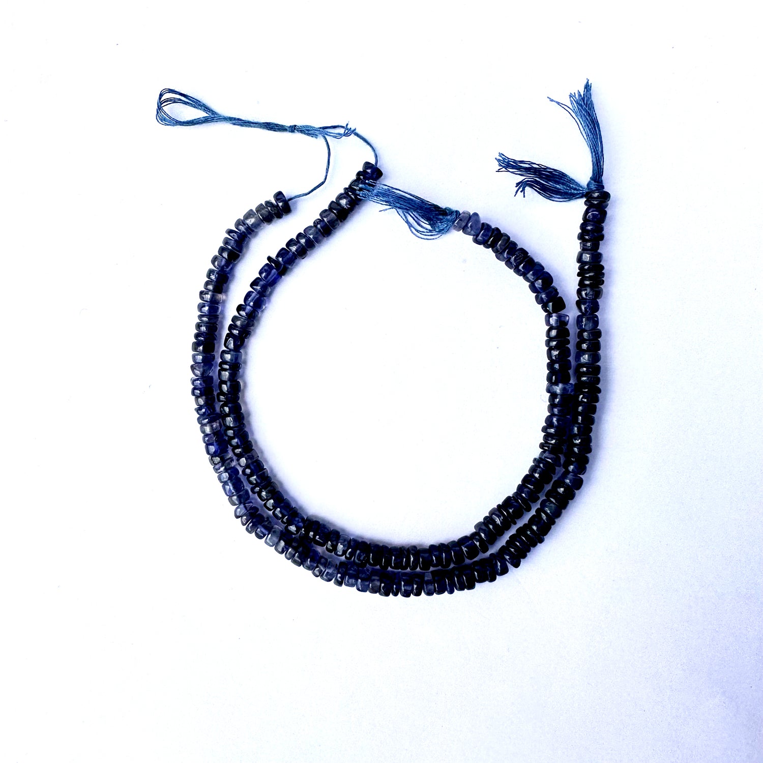 Smooth Iolite wheel beads with rich violet-blue colour and polished 4.7–5mm finish.
