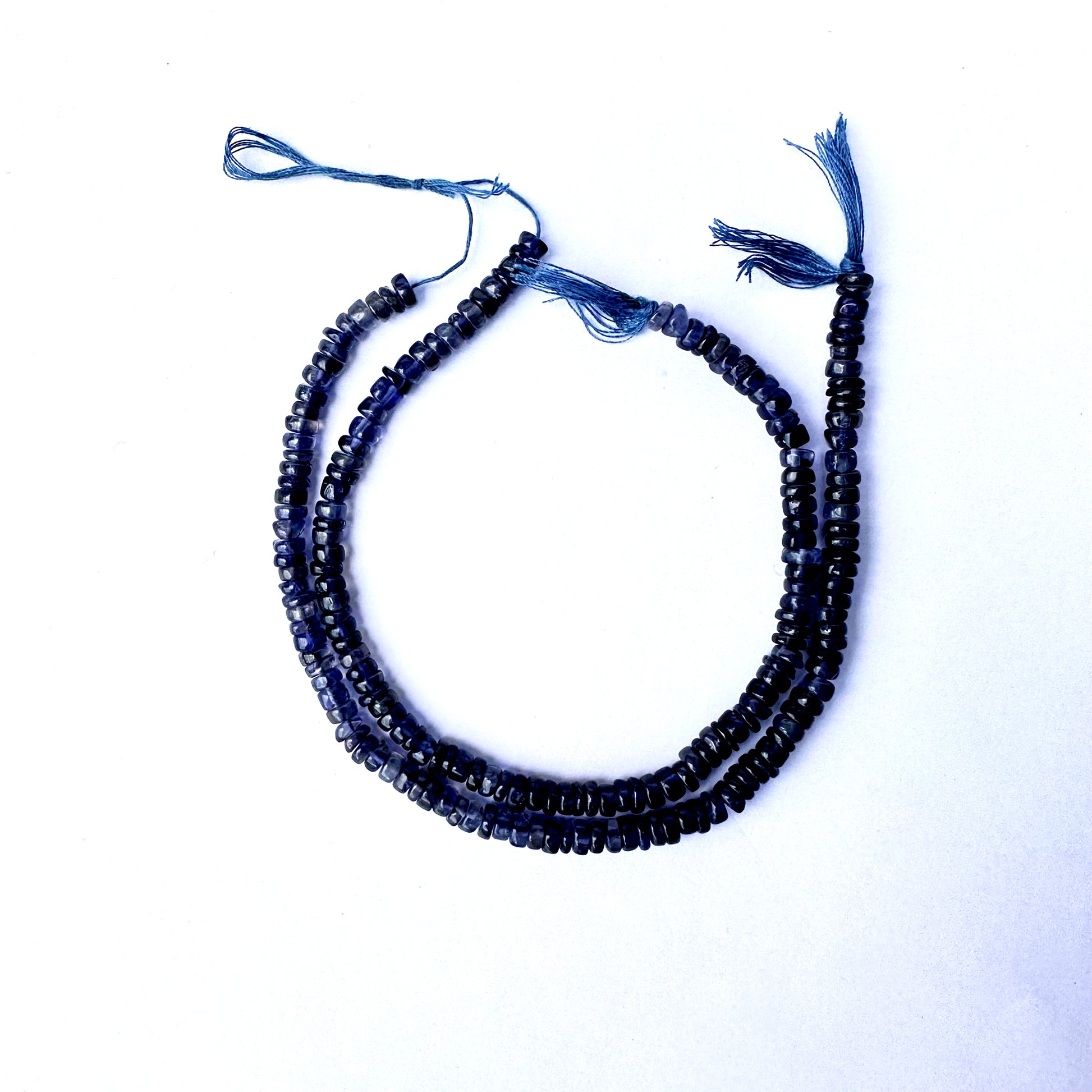 Smooth Iolite wheel beads with rich violet-blue colour and polished 4.7–5mm finish.