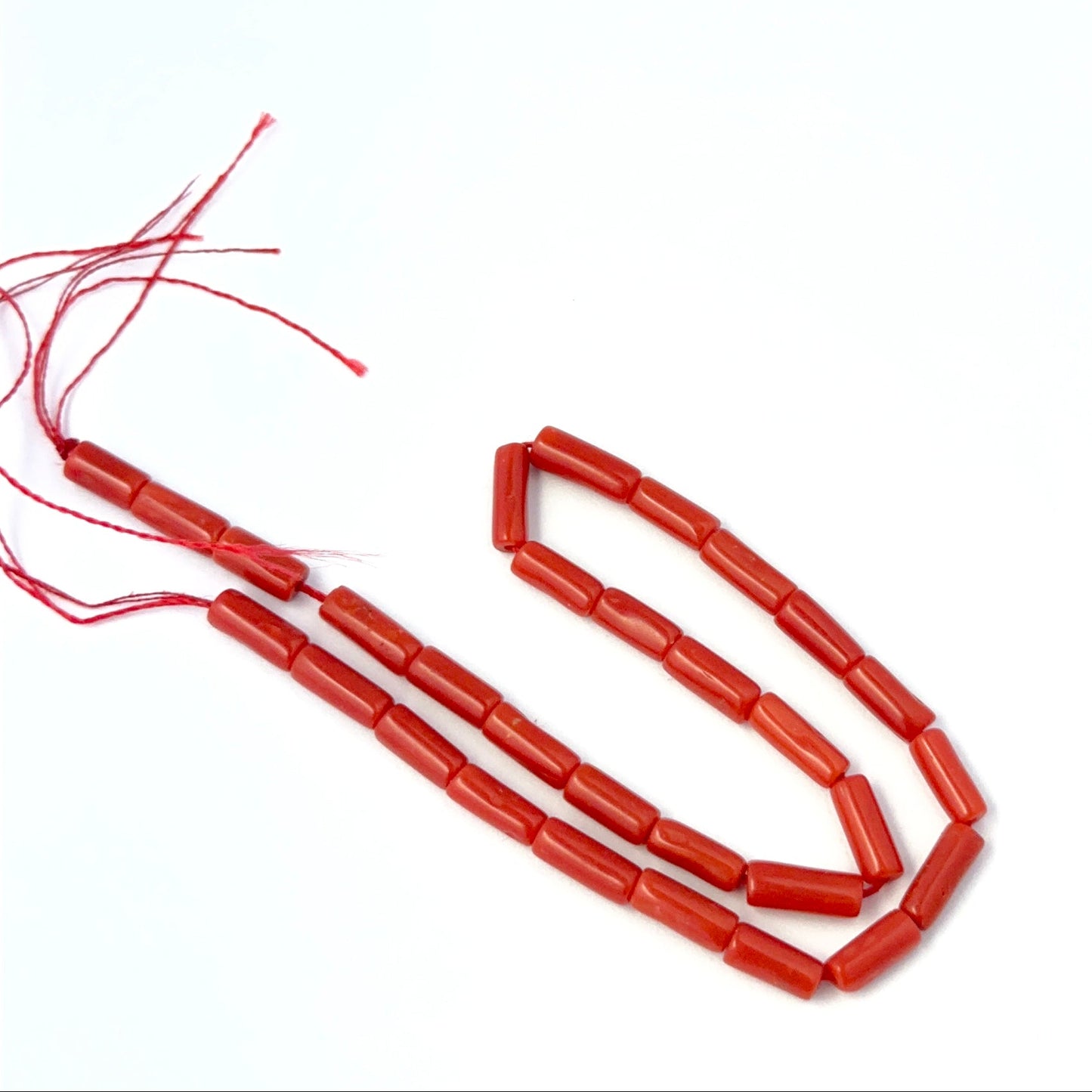 Italian Coral smooth cylinder beads in 3.5mm or 4mm size arranged neatly for DIY jewellery making.