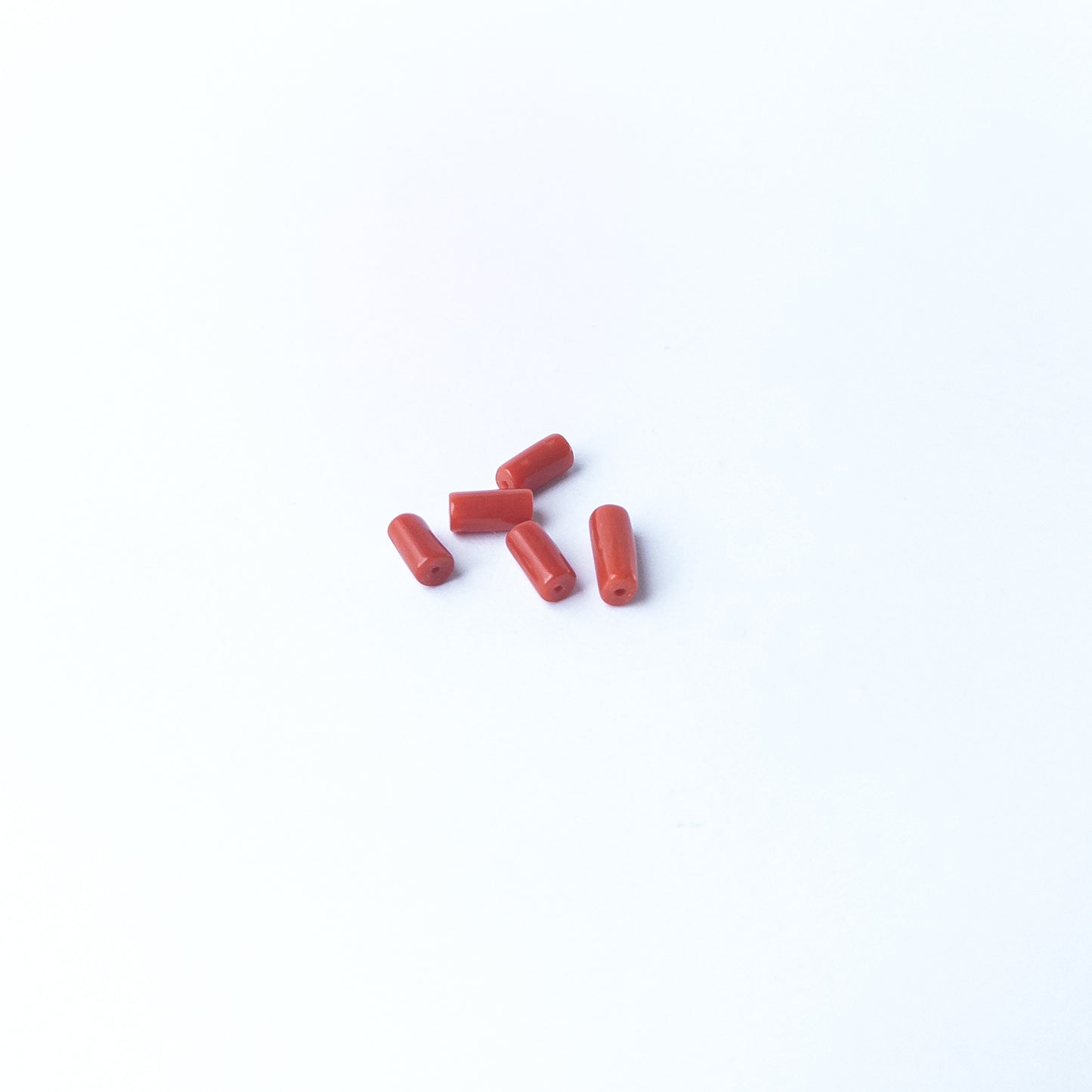 Smooth Italian Coral gemstone beads arranged neatly, offering classic colour for handmade jewellery components.