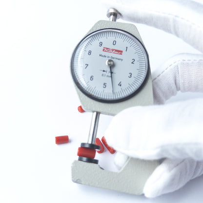 A dial gauge measures the Italian Coral smooth cylinder 4.4–4.5mm bead size gemstone.