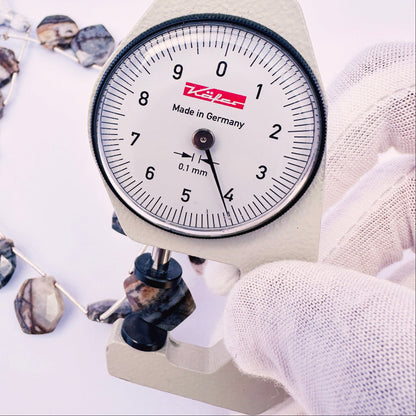 A dial gauge measures the Jasper hexagon faceted 13.5–14mm gemstone.