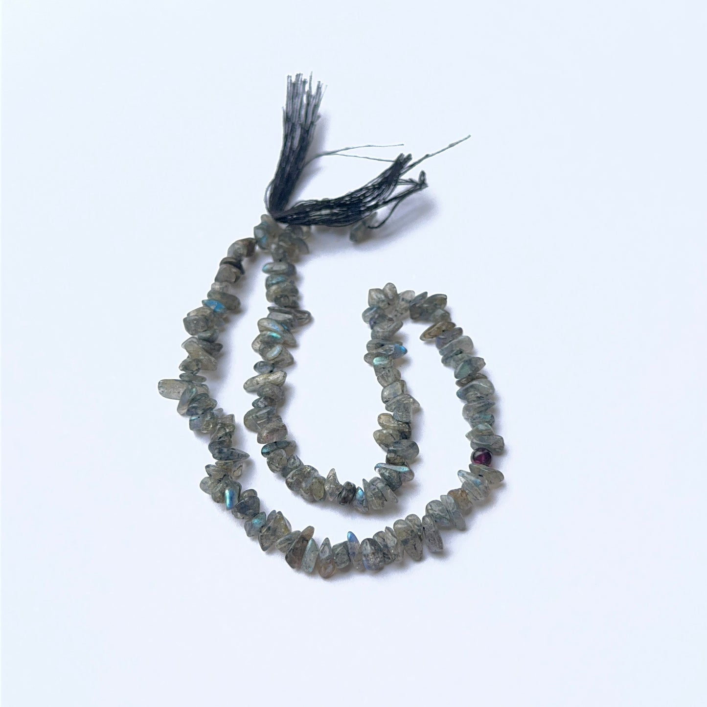 Labradorite 4–4.5mm chip beads arranged on a strand, showing natural colour play and polished surfaces.