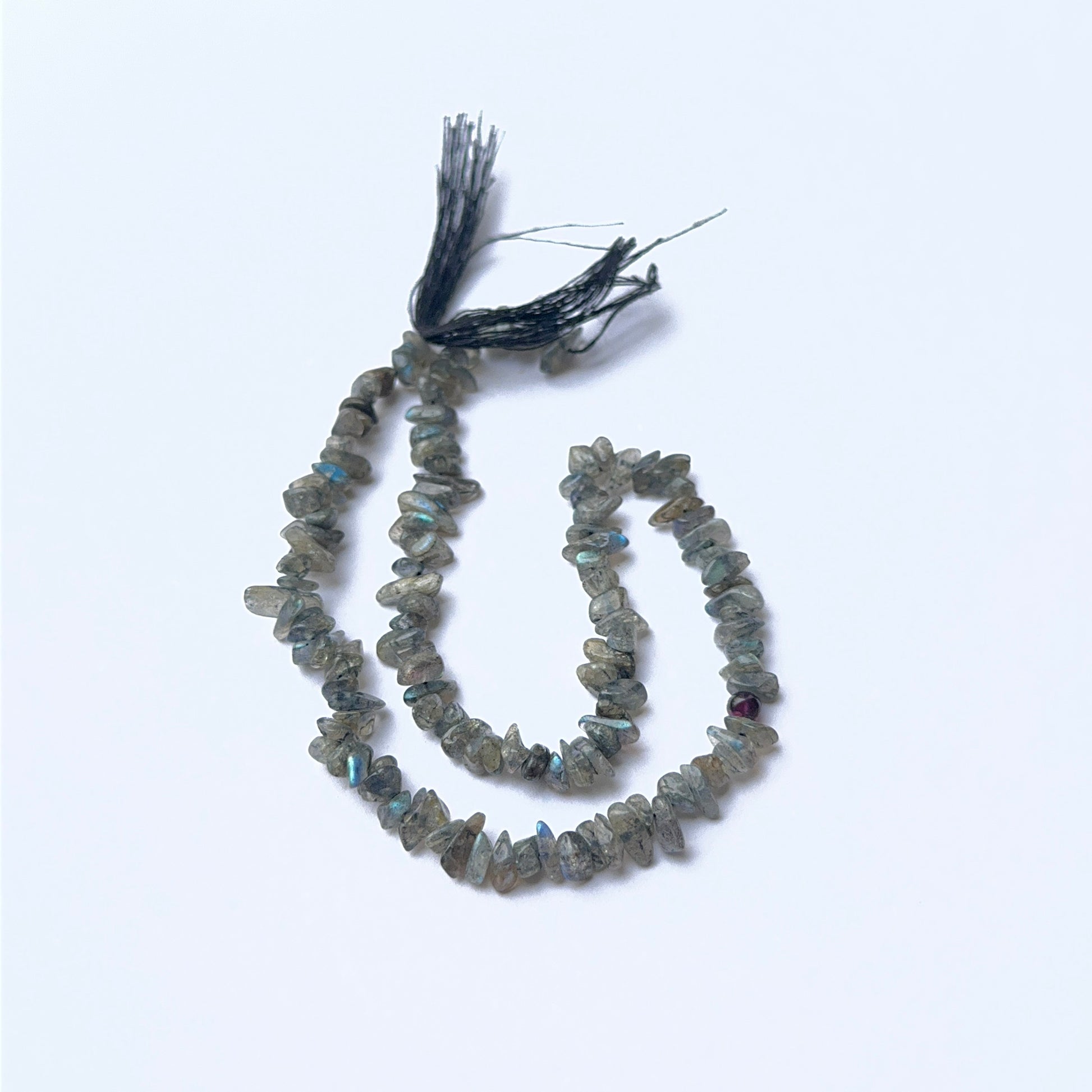 Labradorite 4–4.5mm chip beads arranged on a strand, showing natural colour play and polished surfaces.