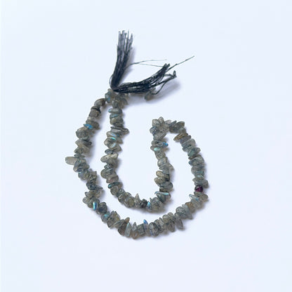 Labradorite 4–4.5mm chip beads arranged on a strand, showing natural colour play and polished surfaces.