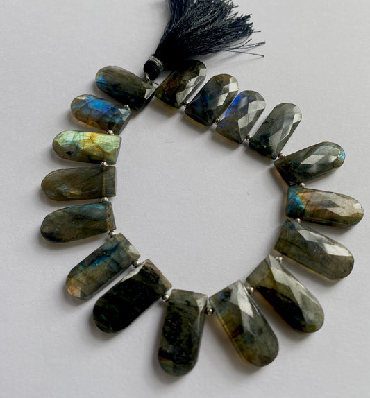 A strand of faceted briolette pentagon labradorite beads with shimmering blue and green hues.