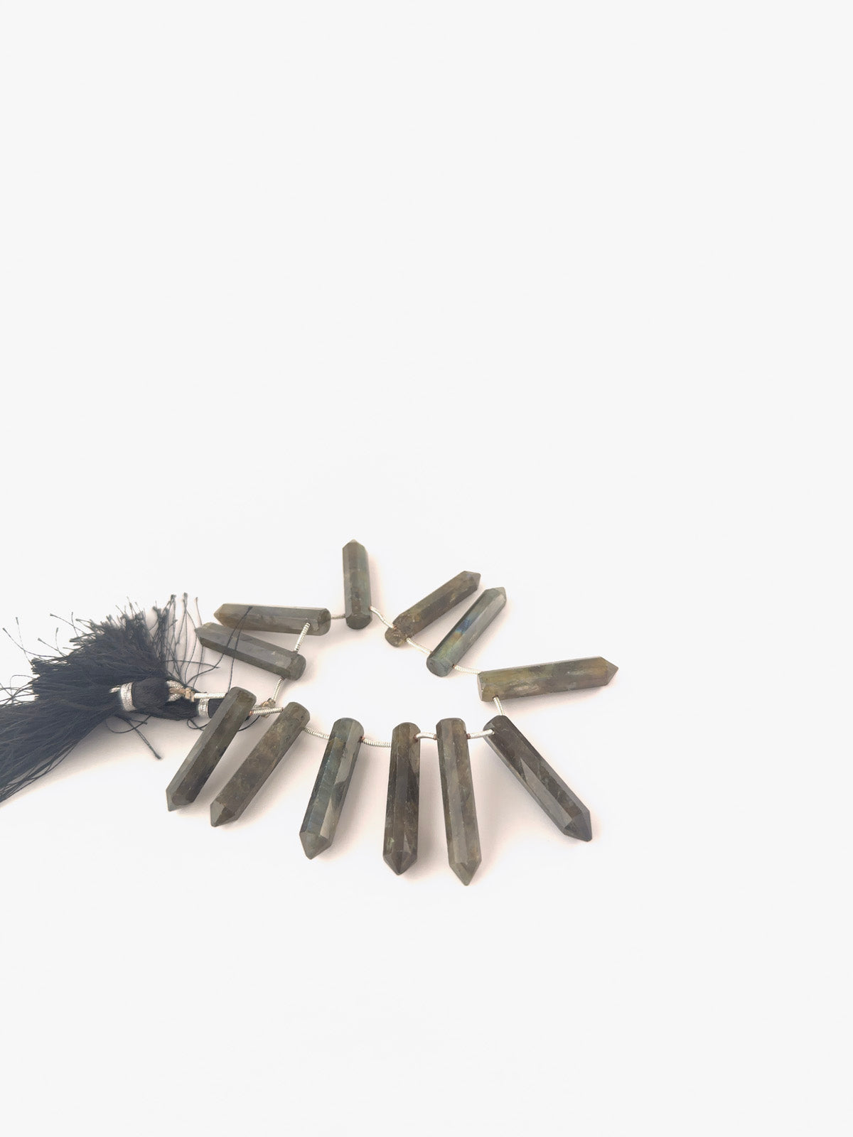 Labradorite pencil‑cut briolette gemstones with elongated tapered shaping and reflective facets across 11 pieces.