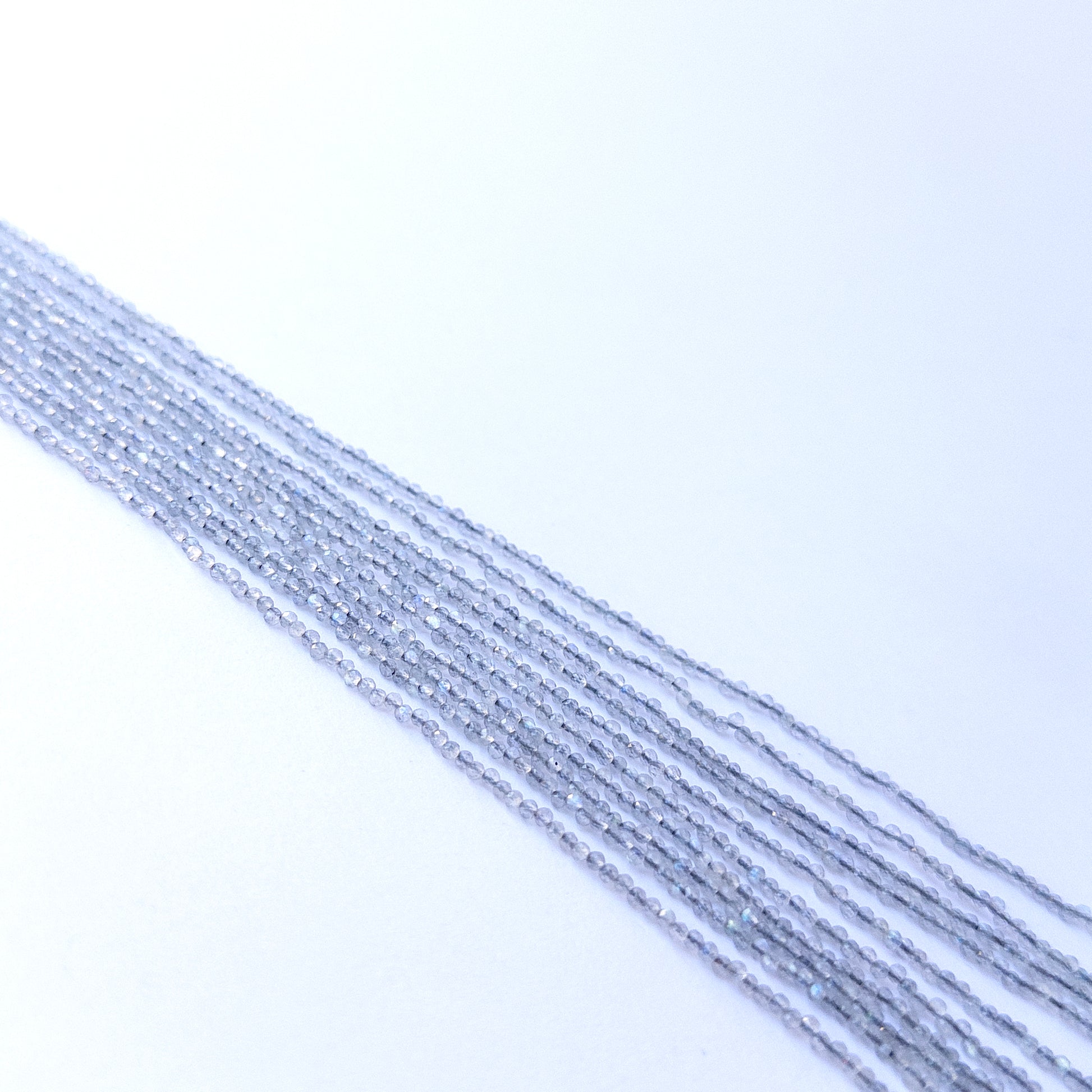 Strands of Labradorite faceted rondelle gemstone beads arranged neatly, showcasing their shimmer and fine cut.