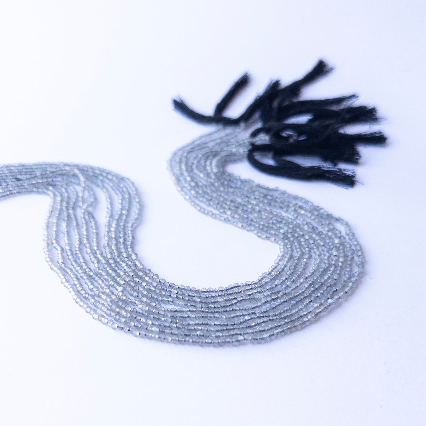 Strands of Labradorite faceted rondelle gemstone beads arranged neatly, showcasing their shimmer and fine cut.