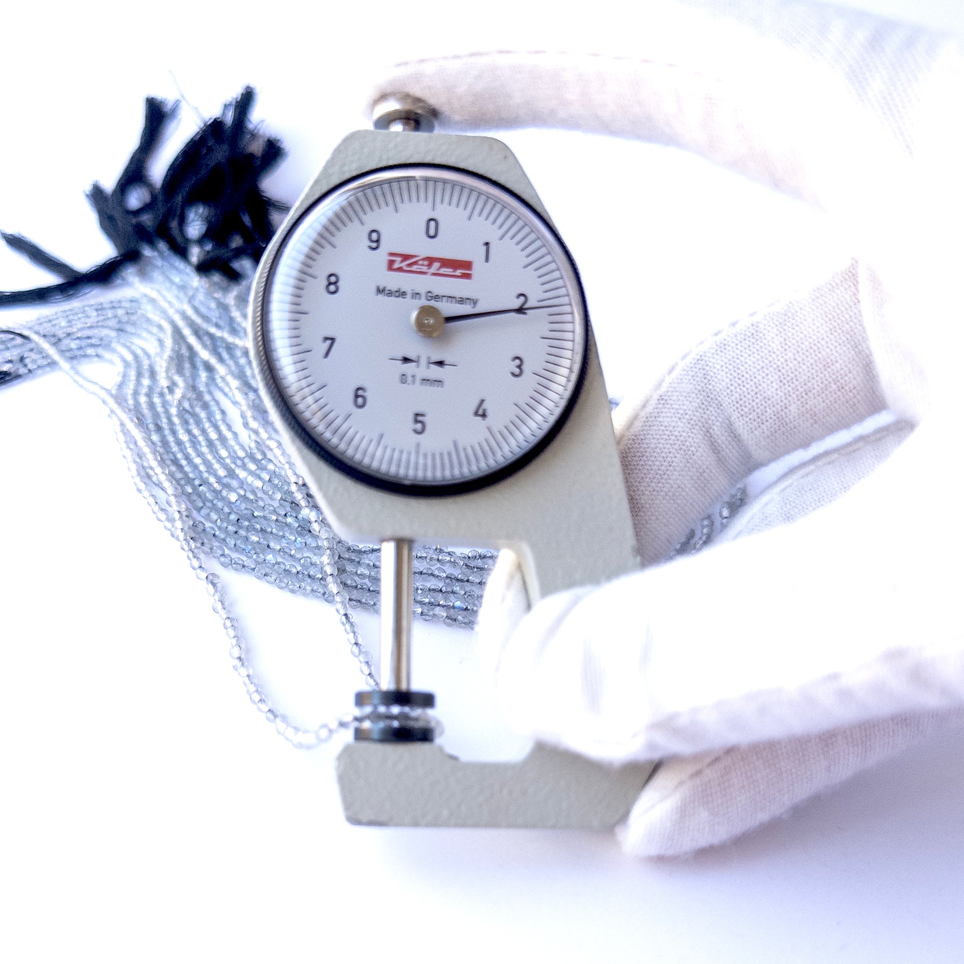 A dial gauge measures the Labradorite faceted rondelle 2.1mm gemstone bead.