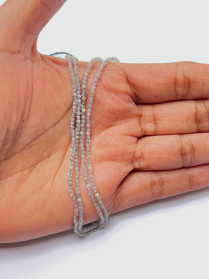 A person holds delicate strands of Green Opal beads, showcasing their smooth design.