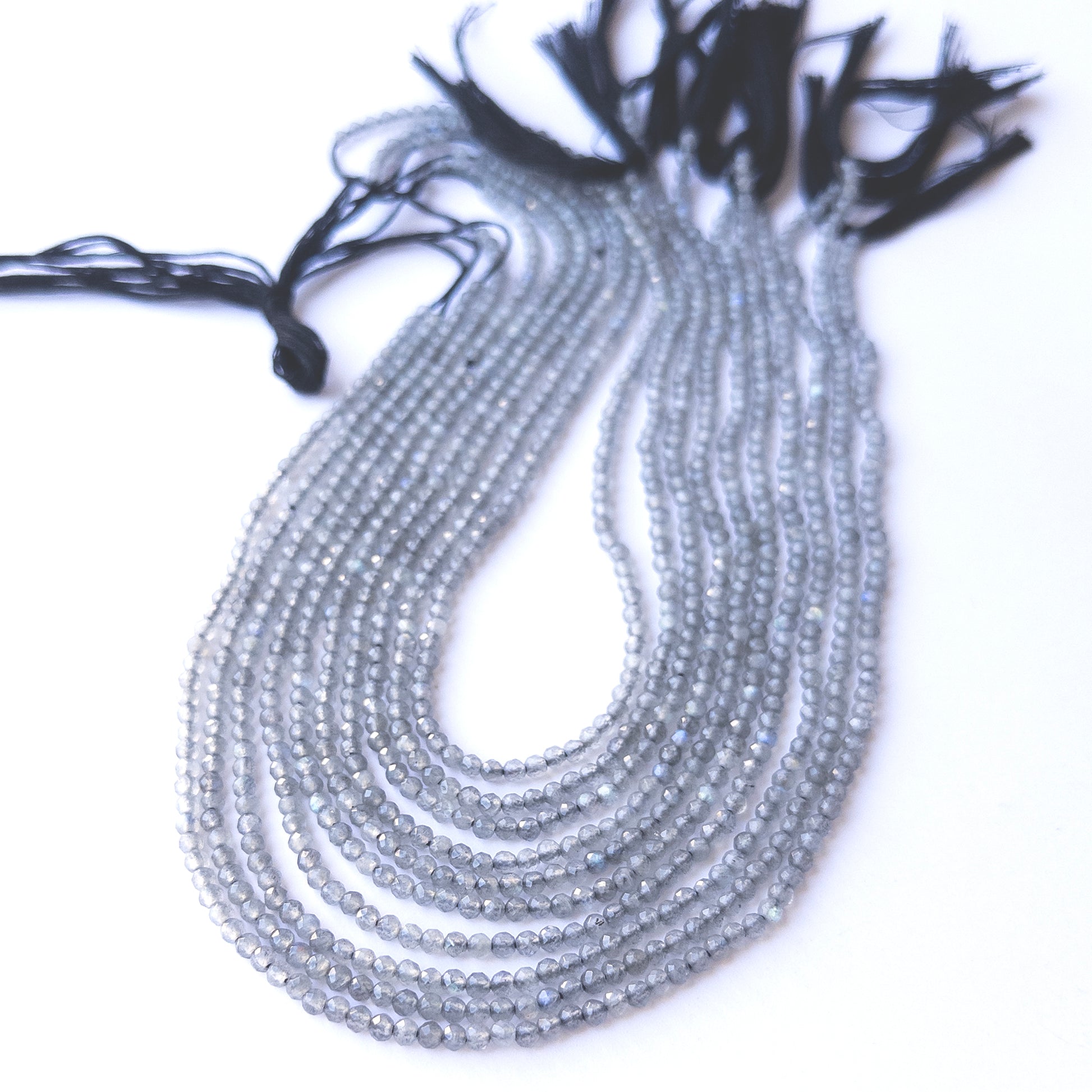 Premium Labradorite gemstone beads in faceted rondelle cut arranged in strands, showcasing natural blue flashes for jewellery designers.