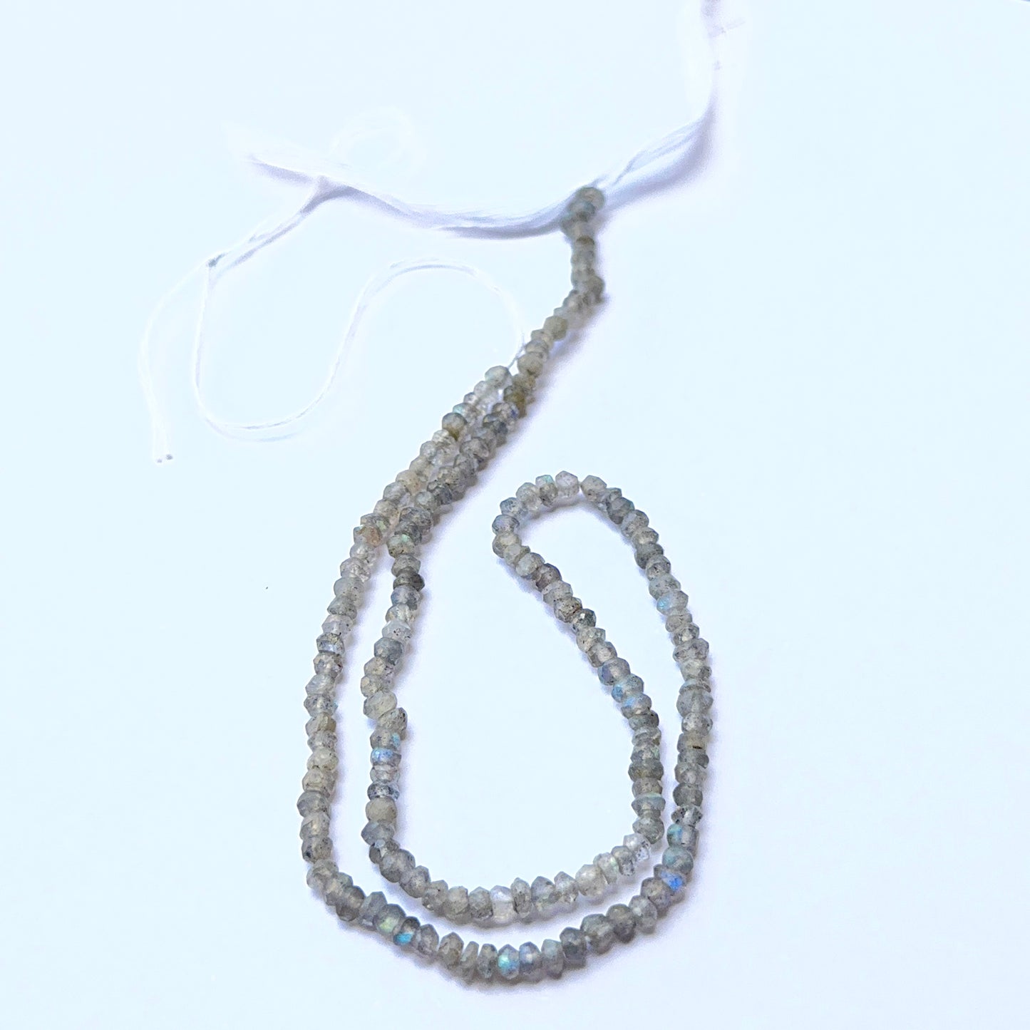 Labradorite 3.1–3.3mm faceted rondelle beads arranged on a strand, showing crisp faceting and natural iridescence.