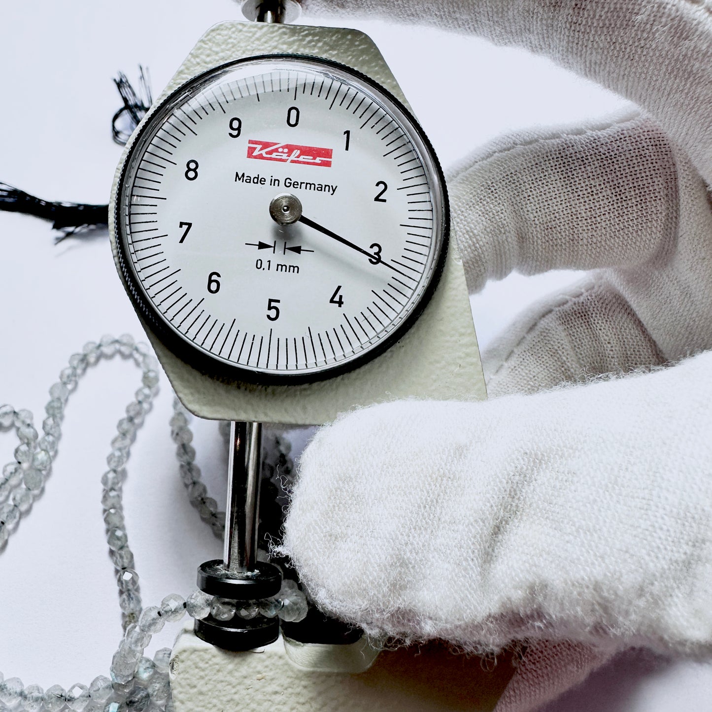 A dial gauge measures the Labradorite faceted rondelle 3.1mm gemstone.