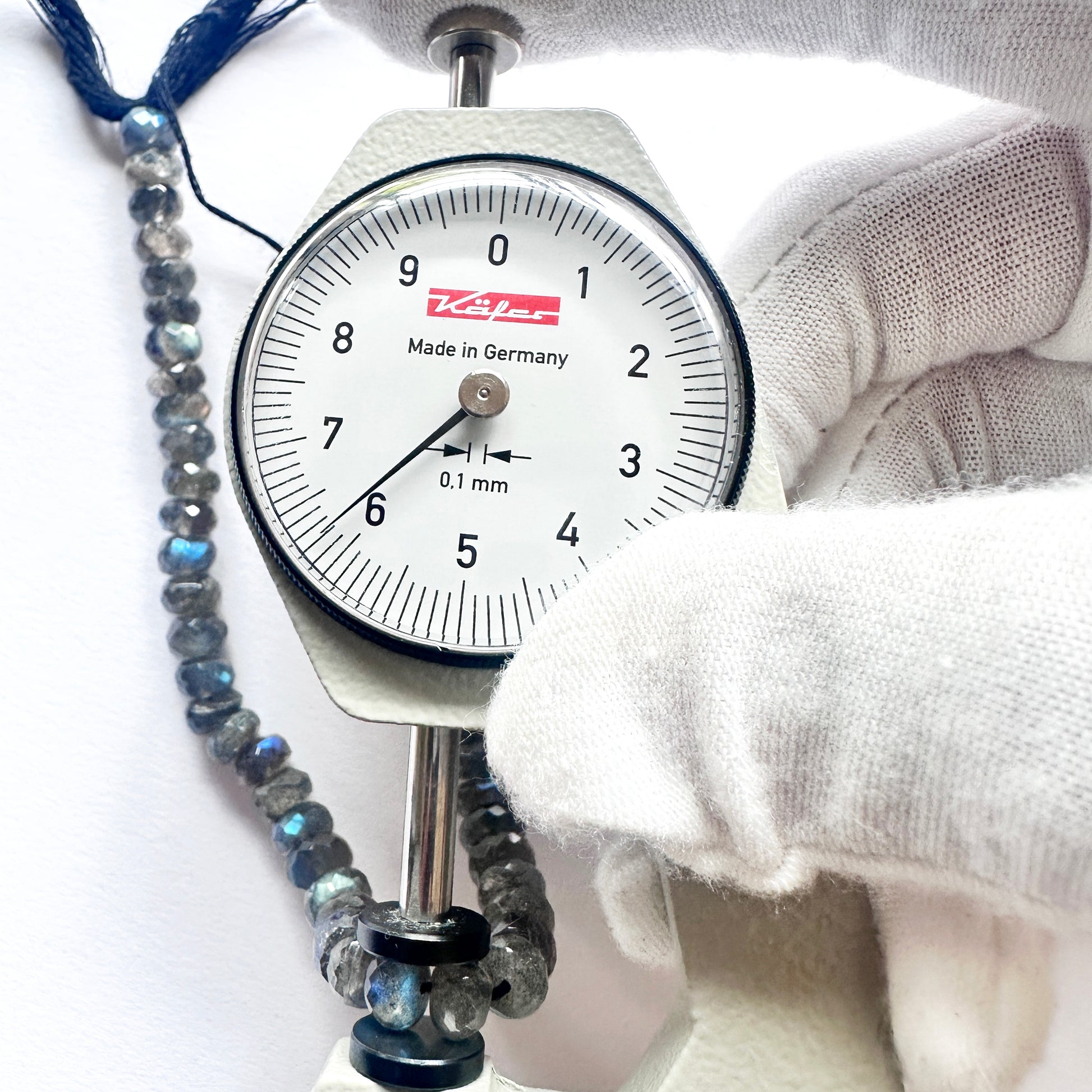 A dial gauge measures the Labradorite faceted rondelle  gemstone.